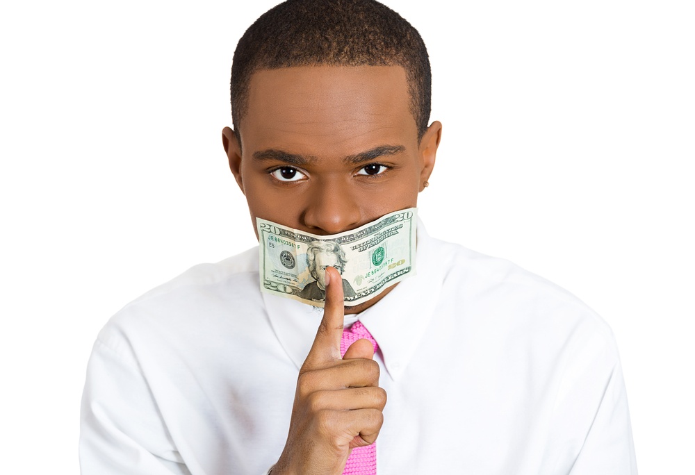 Closeup portrait young corrupt man with cash, dollar, money bill taped to mouth, showing shhh sign, isolated white background. Bribery concept in politics, business, diplomacy. Life perception